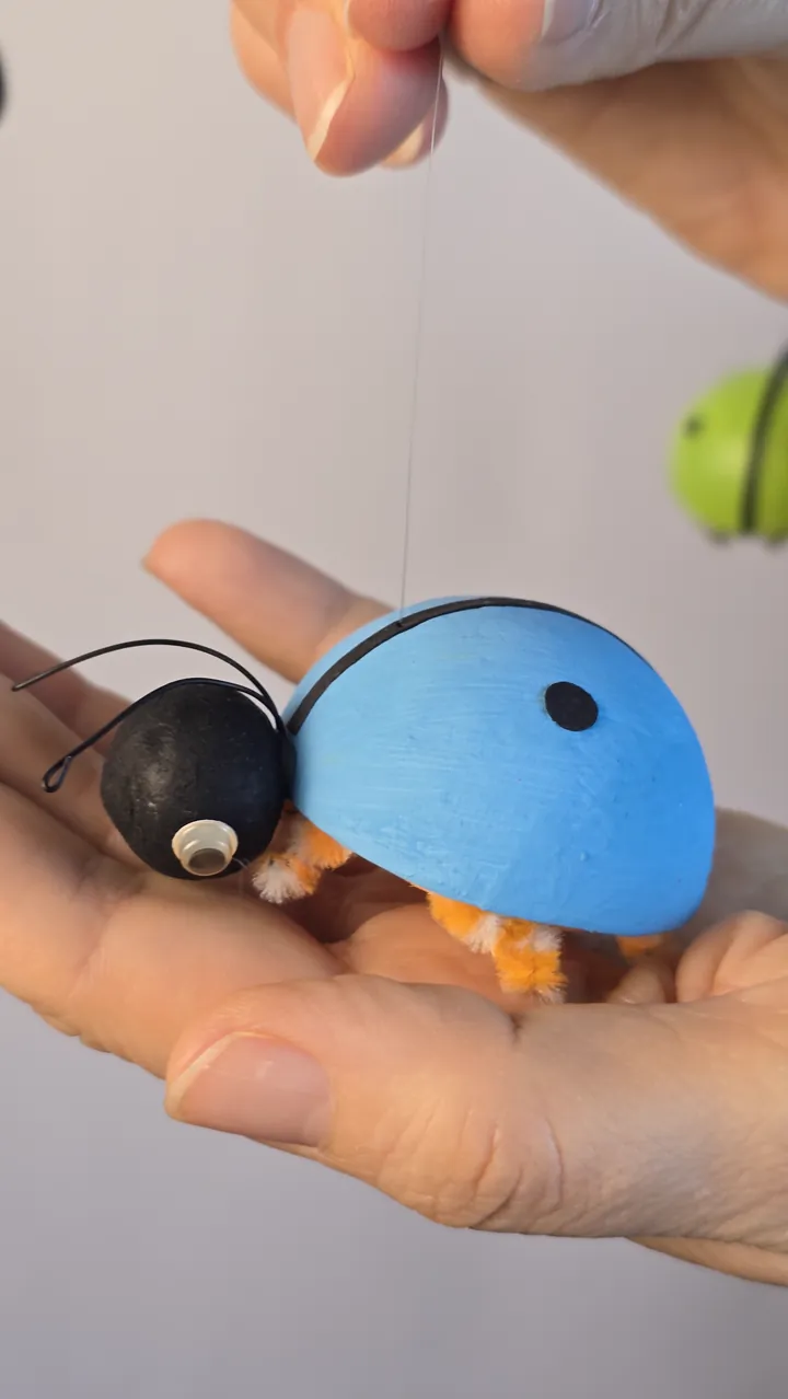 Mobile coccinelles - mains de Clotilde présentant le mobile