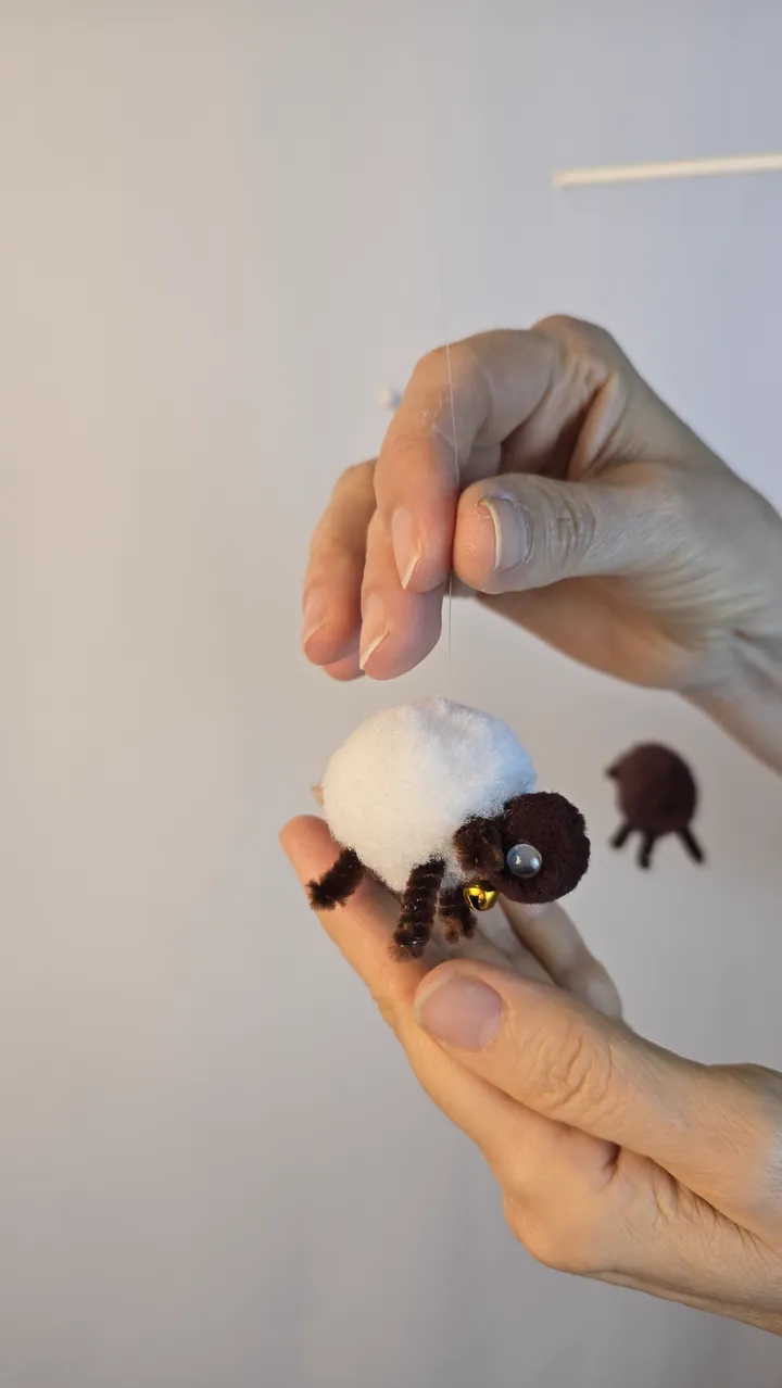 Mobile moutons naturels - mains de Clotilde présentant le mobile