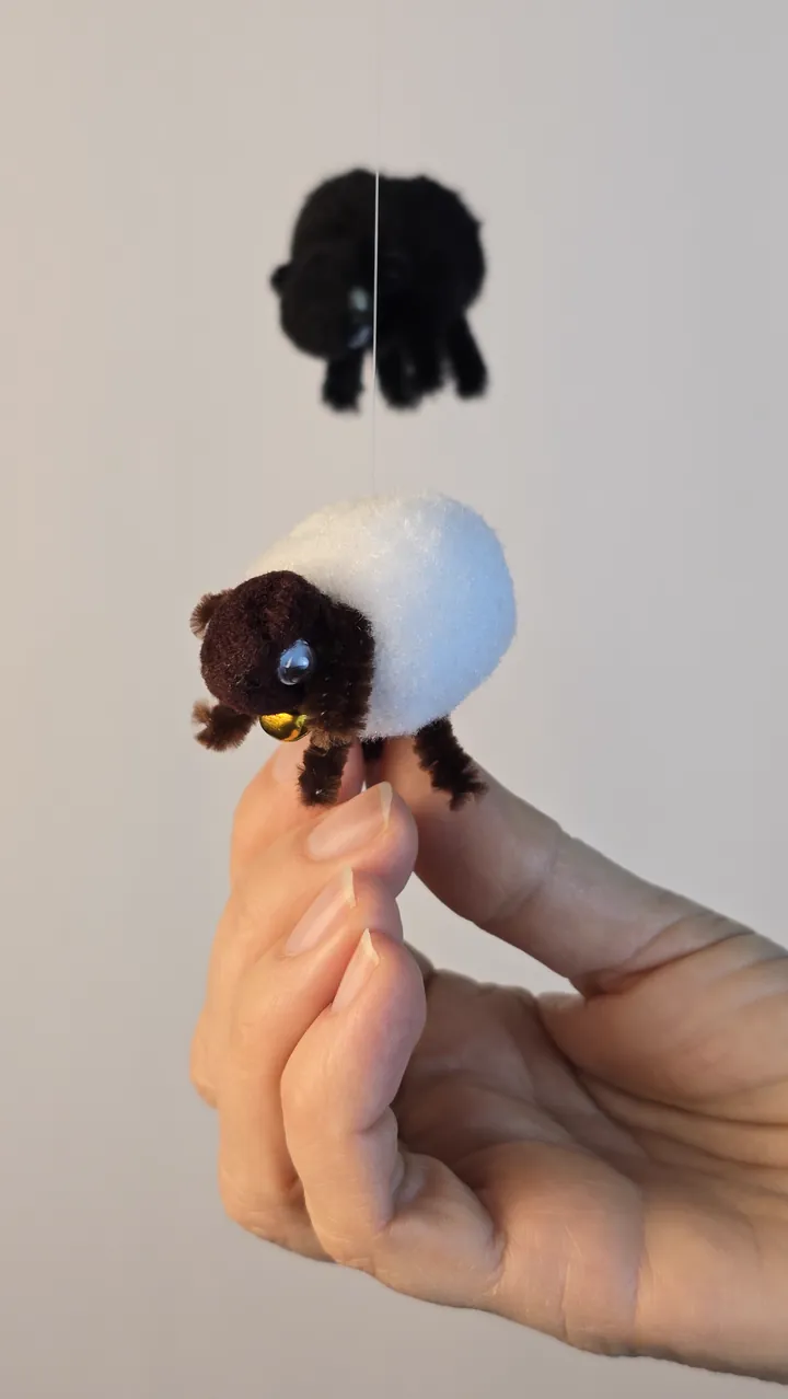 Mobile moutons naturels - main de Clotilde tenant un petit mouton en pompons