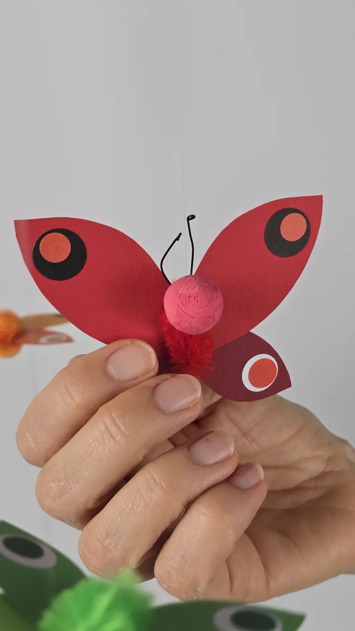Mobile Farandole de Papillons - main de Clotilde tenant un papillon
